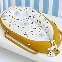 Babiesoul baby nest sleep pod with elephant print and mustard yellow trim on a white crib mattress