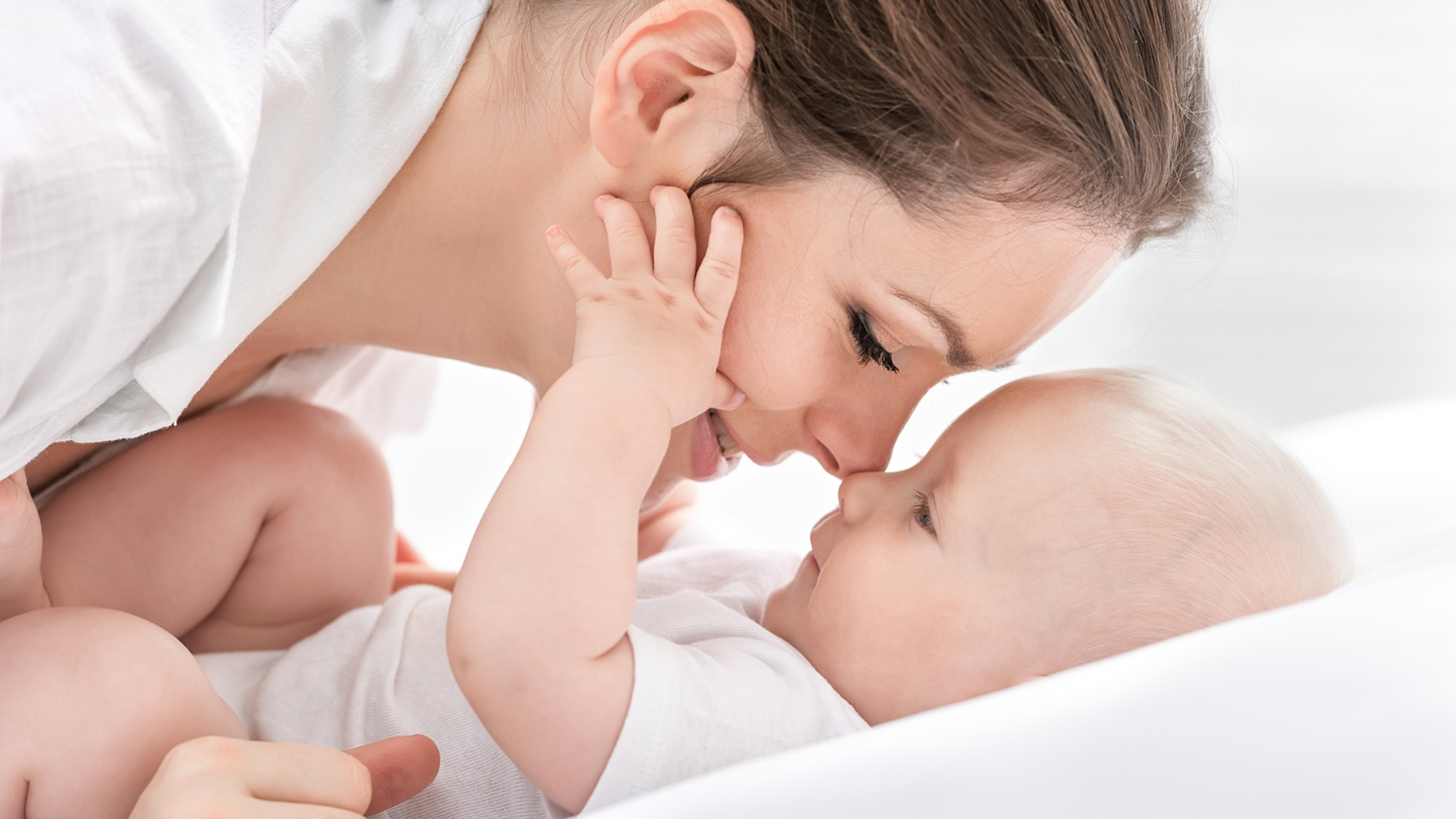 Mother bonding with baby lying in a soft white baby nest sleep pod by Babiesoul