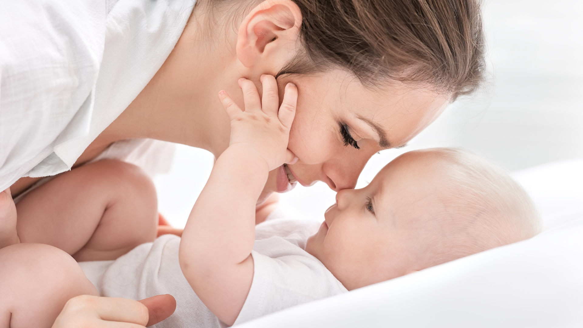 Mother bonding with baby lying in a soft white baby nest sleep pod by Babiesoul
